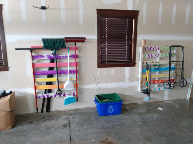 Pallets painted in bright children's designs hanging on the wall to hold shovels and other yard equipment